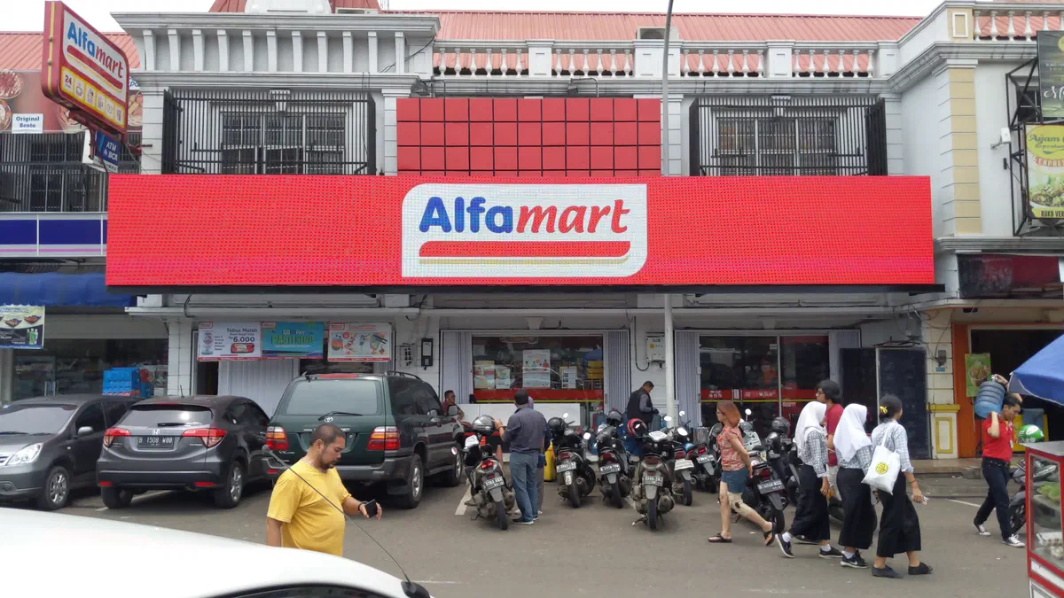 Wide red LED screen above a convenience store showing the store's logo