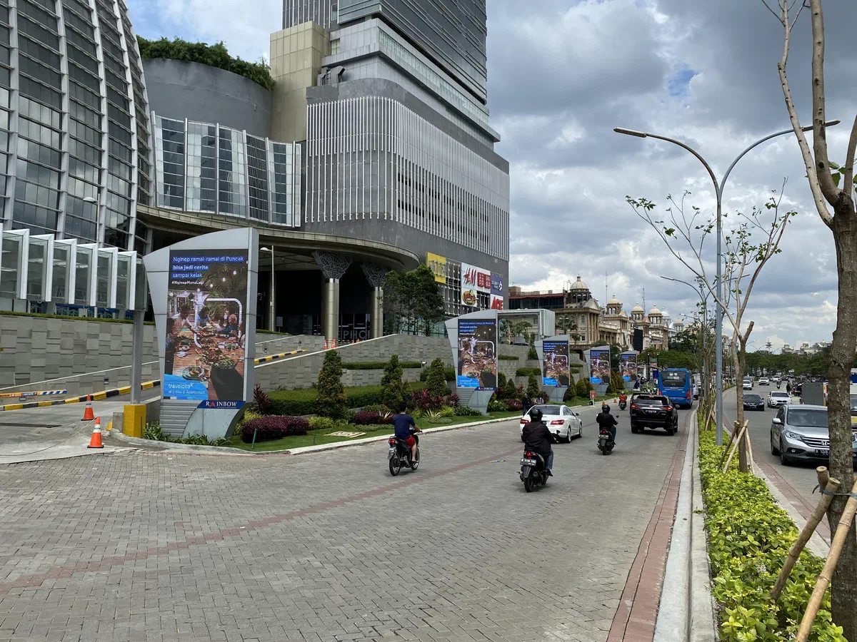 A row of tall LED pylons showing a travel ad along a road outside a shopping mall